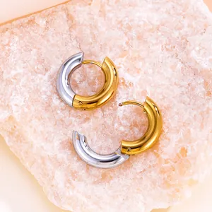 Détail de boucles d'oreilles créoles bicolores en acier inoxydable or et argent