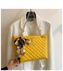 Yellow quilted chain shoulder bag with a silk scarf bow on a white blazer prop