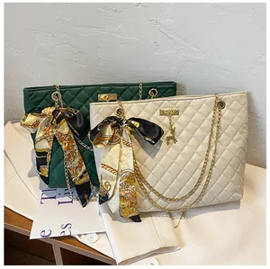 Close-up detail of quilted chain shoulder bags featuring decorative silk scarf bows and gold deer charm