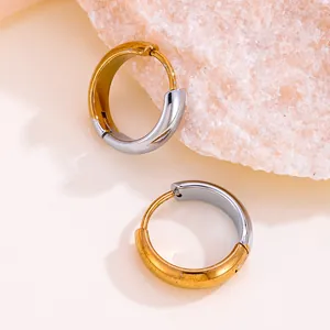 Gros plan détaillé sur des boucles d'oreilles créoles bicolores en or 18 carats et acier