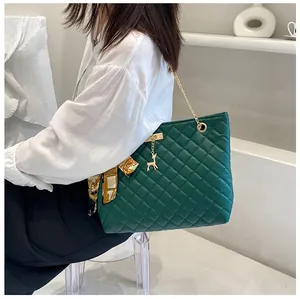 Chic dark green quilted chain shoulder bag with silk scarf detail worn by a model