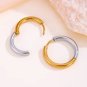 Détail de boucles d'oreilles créoles bicolores en acier inoxydable or et argent.