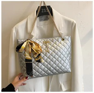 Detailed view of silver quilted shoulder bag with silk scarf bow and gold chain