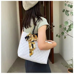 Model wearing a white quilted shoulder bag with a gold chain strap and silk scarf bow