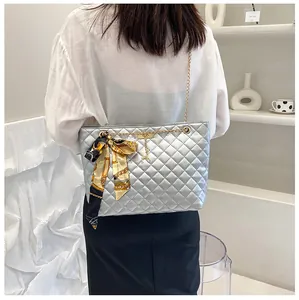 Detailed view of a silver quilted shoulder bag featuring a metal chain strap and scarf
