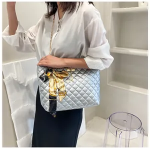 Close-up of a silver quilted shoulder bag with a silk scarf bow and a gold chain strap
