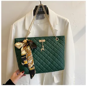 Elegant dark green quilted shoulder bag with floral silk scarf and golden chain strap
