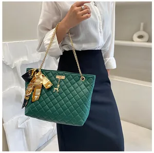 Close-up of elegant green quilted bag with gold chain strap and silk scarf accessory