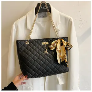 Detailed view of black quilted shoulder bag with gold chain and decorative silk scarf