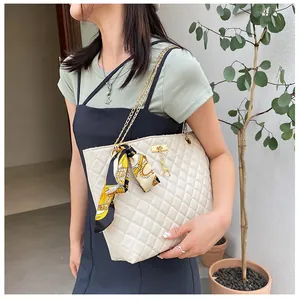 Close-up detail of a cream quilted chain bag with a silk scarf and a gold deer charm