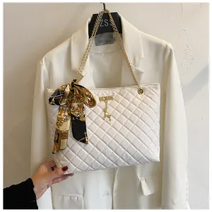Detail of white quilted handbag with gold chain strap and decorative silk scarf.
