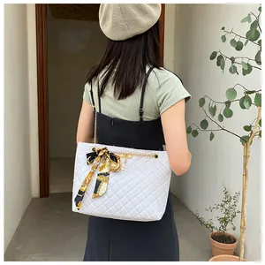 Back view of a white quilted shoulder bag with chain strap and silk scarf detail