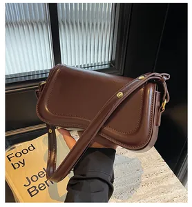 Detailed view of a chocolate brown leather underarm bag with elegant gold hardware