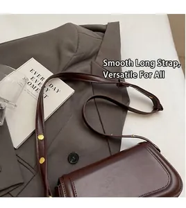 Detail view of brown leather shoulder bag with adjustable strap and gold hardware