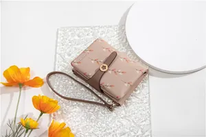 Close-up of pink women's bifold wallet with leaf print and buckle strap detail