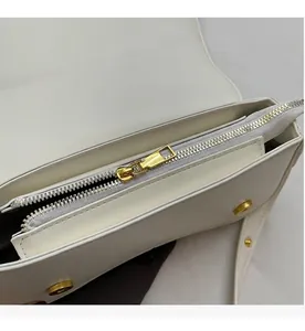 Detailed close-up showing the smooth golden metal zipper of a white women's shoulder bag