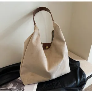 Detailed view of an elegant beige suede tote bag with a brown leather shoulder strap