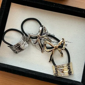 Close-up of elegant metallic alloy bow and textured rectangular hair ties in gold and silver