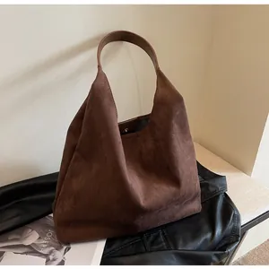 Elegant brown faux suede shoulder bag displayed on a leather jacket with modern aesthetic.