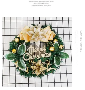 Vue détaillée d'une couronne de Noël artificielle de 30 cm avec un nœud doré et un signe