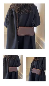 Detailed view of the brown underarm bag worn over a black coat from the back.
