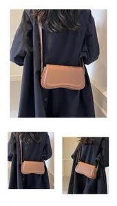 Close-up view of a brown minimalist baguette shoulder bag with a unique curved base