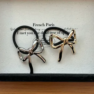 Macro view of metallic bowknot hair ties in gold and silver finishes on a paper card