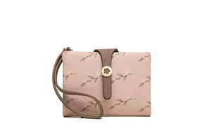 Detailed view of a pink women's bifold wallet featuring floral prints and a wristlet
