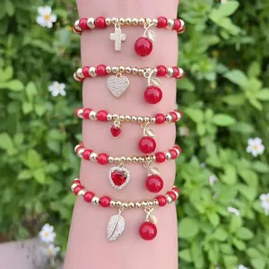 Set di cinque braccialetti di perline rosse con ciondoli a ciliegia e cuore in oro