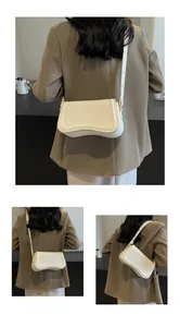 Back view of a minimalist white crossbody bag with unique wavy bottom design