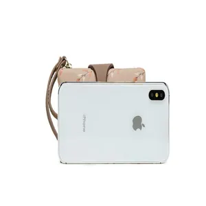 Floral print women's short wallet with wrist strap next to phone for size reference