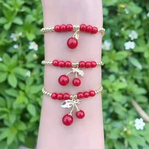 Set di braccialetti con perline e ciondoli a ciliegia rossa con accenti dorati al polso