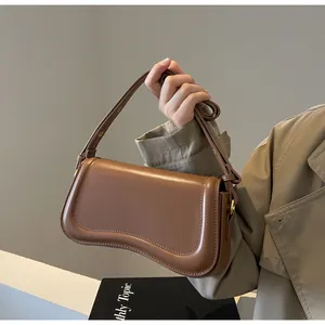 Minimalist brown faux leather shoulder bag with unique curved bottom detail.