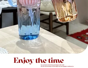 Close-up detail of gradient glass water bottle with pink tea infuser on a wooden table