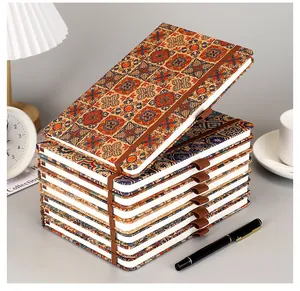 A stack of eco-friendly cork notebooks featuring vintage Bohemian floral patterns