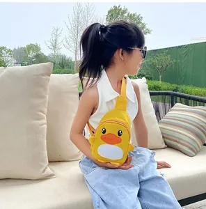 Une petite fille porte un sac à bandoulière mignon en canard jaune à l'extérieur.
