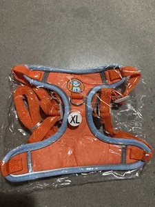 Detail view of orange reflective dog harness with XL size label in clear packaging.