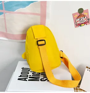 Vue détaillée d'un sac à bandoulière canard jaune pour enfants sur un livre blanc