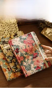 Primer plano de cuaderno vintage de pana con estampado floral y cierre elástico.