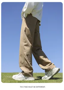 Detail view of men's loose straight cotton khaki pants in a sunny outdoor setting