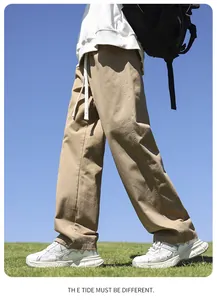 Detailed view of men's loose khaki cotton casual pants shown in a sunny outdoor setting.