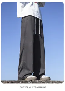 Detailed view of men's loose dark grey cotton wide-leg pants with drawstring waist
