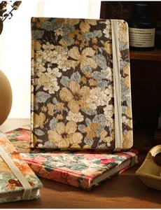 Close-up of vintage corduroy floral notebook with elastic strap closure in a cozy setting.