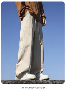 Full length view of men's beige wide-leg cotton casual pants styled with white sneakers.