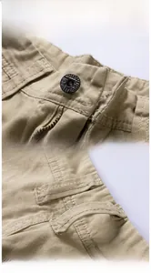 Detailansicht von robustem Metallknopf und Reißverschluss an Khaki-Cargo-Shorts.