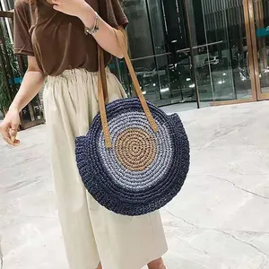 Detail shot of a stylish round woven straw shoulder bag featuring a blue gradient design