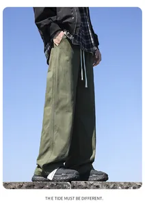 Detailed side view of men's olive green wide-leg cotton trousers against a clear blue sky