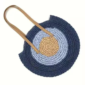 Close-up of bohemian round straw woven shoulder bag with concentric circular pattern