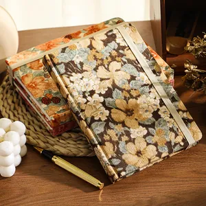 Vintage A5 corduroy notebook with floral fabric cover and elastic closure on wooden desk.