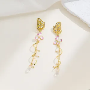 Close-up of elegant gold butterfly earrings with pink flowers, pearls and crystal drops